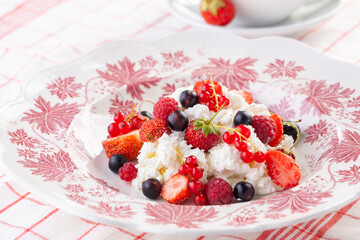 dessert with fresh berries on a red vintage plate. Farm cottage cheese
