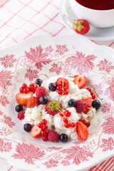 dessert with fresh berries on a red vintage plate. Farm cottage cheese