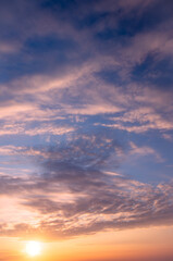 A bright sunset against the background of a blue sky and cirrus and cumulus clouds.