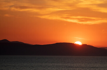 Sunrise, sunset clouds. Twilight, dusk cloudy sky over sea water, dark land horizon