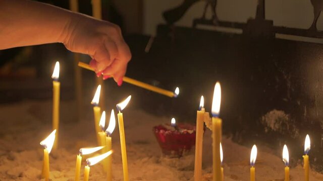 Woman with candle in temple hand closeup orthodox church interior slow motion