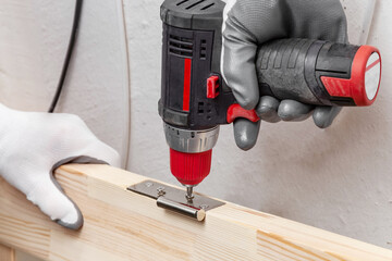 Close up of a carpenter screwed a hinge on a wooden plank