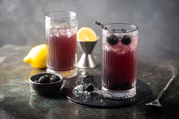 Refreshing Blackberry Lemonade with ice in crystal glasses on gray background
