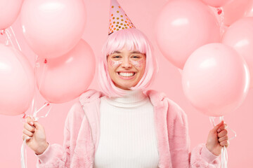 Young happy teen girl holding many pink balloons in hands and enjoying birthday party