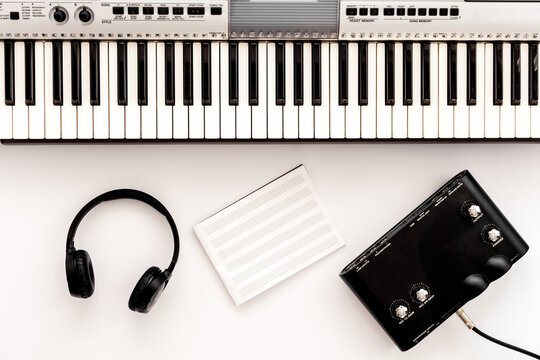 Musician work set with synthesizer, note and headphones Yellow table background top view space for text