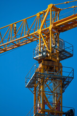 Yellow tower crane working on building against blue sky, selective focuse