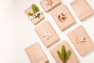 pattern of several Christmas gift boxes in eco friendly style on a white background, decor from wooden Christmas tree toys, dried orange and spruce branch