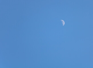 The moon in the blue sky during the day