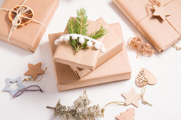 eco style christmas gift wrappers, some gift boxes decorated with wooden christmas tree toys and fresh spruce branch, white background, zero waste lifestyle