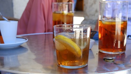 Vaso con bebida fría con hielos y limón en una terraza