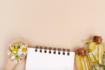 Recipes natural beauty concept. Notebook, essence bottles, petals, daisies flat lay with copy space