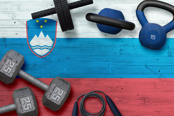 Slovenia sports club concept. Top view of heavy weight plates with iron bar on national background.
