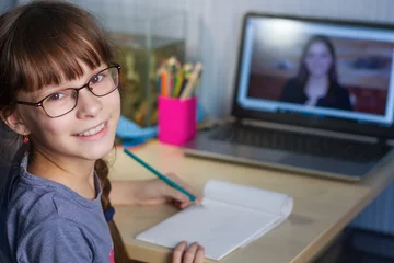 Foto op Canvas Online onderwijs op afstand. Een gelukkig meisje studeert thuis en maakt huiswerk op school. © Albert Ziganshin