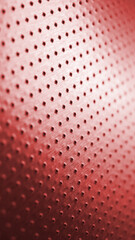 Tinted red metal background with bright saturated color. Dark vertical wallpaper for mobile. Perforated aluminum surface with many holes. Their ranks go into the distance and form a perspective. Macro