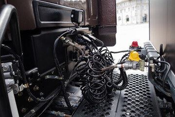 Coiled control and electrical cables connect the cab and semi-trailer of the truck.