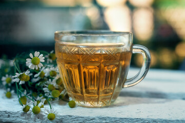 A Cup of tea with chamomile on a wooden background.