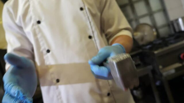 Chef throwing a tenderiser from one hand to another in a kitchen in slo-mo
