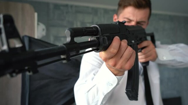 a man in a suit with a tie holds a machine gun in his hands and aims through it