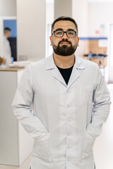 Portrait of a doctor or medical specialist. Vertical portrait. Man in scrubs. Hands in pockets.