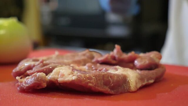 Slice of raw beaf is struck with a metallic mallet in a restaurant kitchen in slo-mo