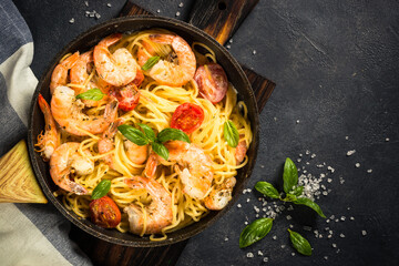 Pasta seafood with shrimp on black table.