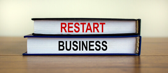 Books with text 'restart business' on wooden table. Beautiful white background. Business concept, copy space.