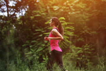 Young fitness woman running in the morning forest trail. Healthy fit living.