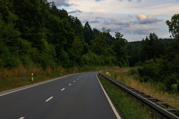 empty asphalt road in Odenwald forest in Germany. Asphalt road with leading lines in green environment.