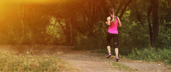 Young fitness woman running in the morning forest trail. Healthy fit living.