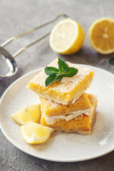 freshly baked lemon bars (or lemon squares) with powdered sugar on grey background, close up