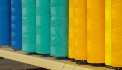 Rolls of colored cotton thread for sewing with machine in store. Background of sewing tools which consist of color buttons.