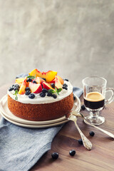Cake with whipped cream and fresh fruits - peaches and blueberries and coffe, round coffe cake, summer celebration birthday cake