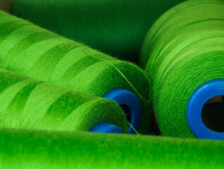 Rolls of green cotton thread for sewing with machine in store. Background of sewing tools which...