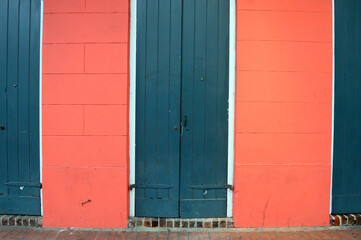 Green doors contrast with the dark pink walls in the French Quarter of New Orleans