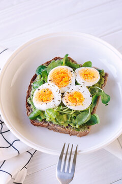 Hard boiled egg on avocado toast with freen leaves, healthy breakfast or lunsh