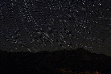 A view of the stars of the Milky Way with a mountain top in the foreground. Night sky nature summer...