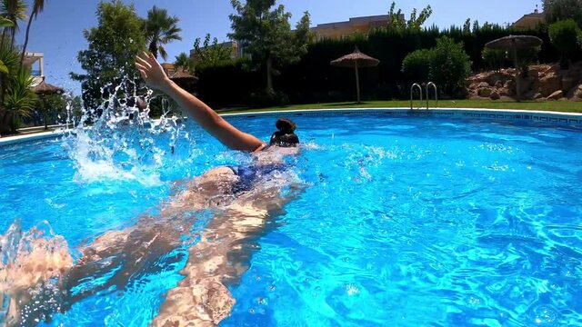 Young girl swimming crol style at residential swimming pool