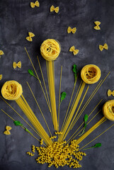 Composition of pasta of different shapes in the form of flowers and butterflies on a dark background
