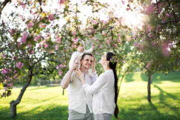 Fototapeta premium Happy man and woman playing with baby outdoors