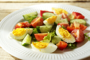 rustic summer salad with fresh cucumbers, tomatoes and eggs on a white plate