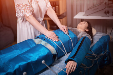 woman lying on body pressotherapy machine in beauty center