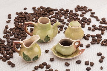 small set of porcelain cups with coffee beans on a wooden table and beans of coffee around