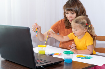 Mother and daughter paint together. Happy family spends time at home.