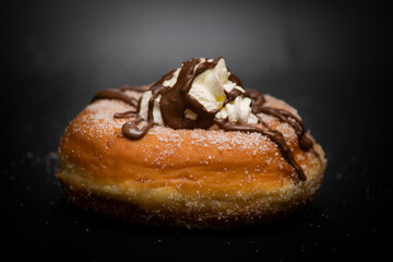 isolated fresh donut in Italian breakfast with sugar, chocolate, and cream on black background