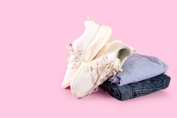Woman's casual summer clothes with white textile sneakers on pink background, sport running shoes with white soles, with copy space