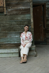 Portrait of a young brunette woman in a white fashion suit with a red print