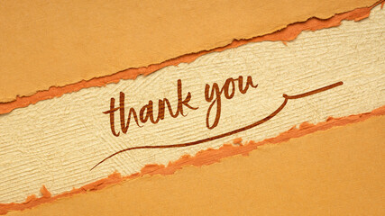 thank you handwriting on a handmade paper in orange and brown tones, web banner