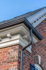 Beige cornice horizontal decorative molding crowning a new brick building with brown metal gutter...