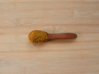 Brown color Garam masala spices on wooden spoon