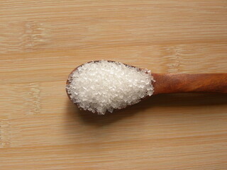 Fototapeta na wymiar White color common refined sugar on wooden spoon